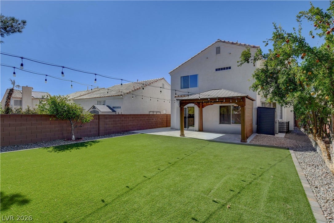 8308 Raphael Court, Las Vegas, NV 89129 A private yard with vibrant artificial turf and a covered patio offers an ideal outdoor retreat.