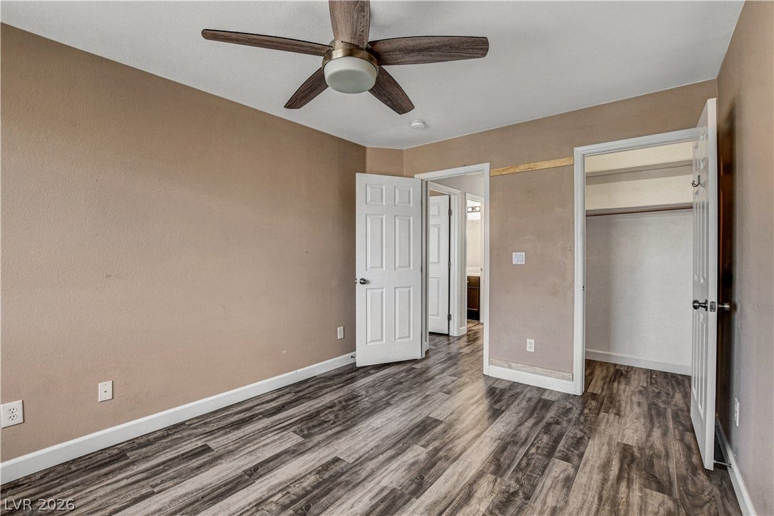 8308 Raphael Court, Las Vegas, NV 89129 A comfortable bedroom features stylish wood flooring and a modern ceiling fan, offering a cool retreat.
