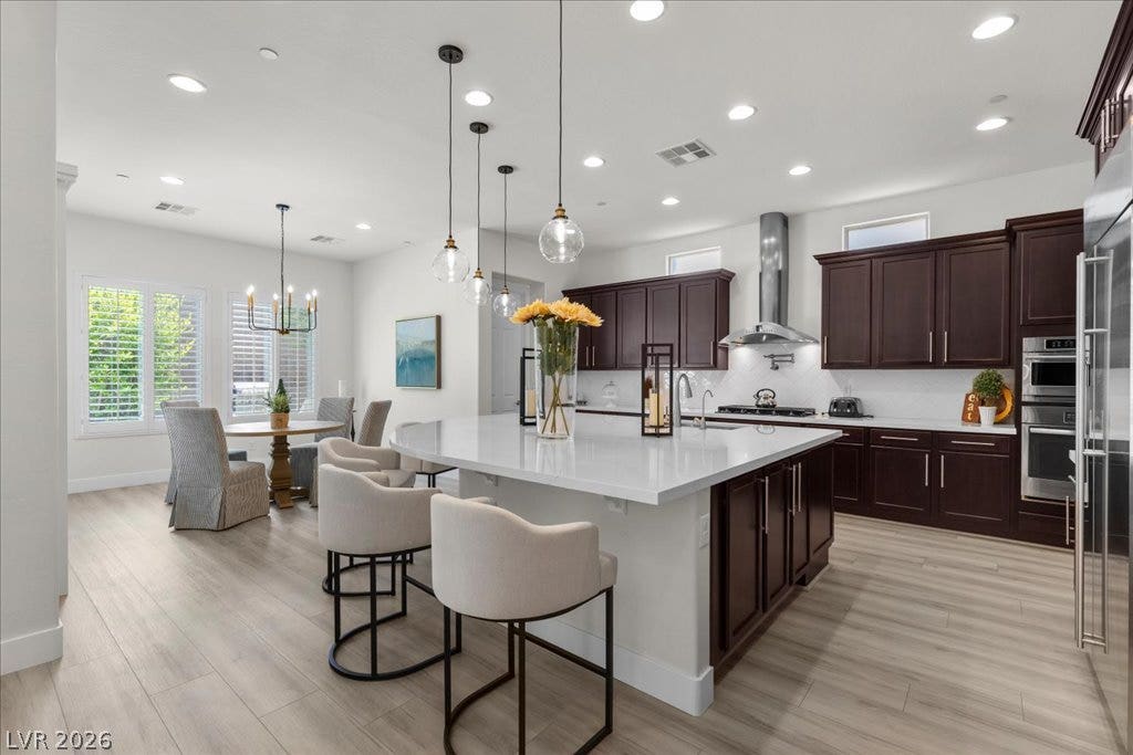 2828 Josephine Drive, Henderson, NV 89044 A contemporary kitchen boasts a spacious island with bar seating, integrated sink, and an adjacent dining area, creating a harmonious open-concept living space.
