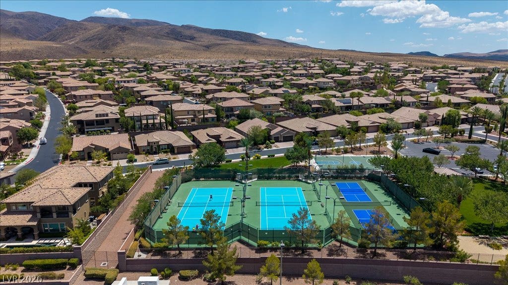 2828 Josephine Drive, Henderson, NV 89044 An aerial perspective reveals a vibrant community with tennis courts nestled among residential rooftops, framed by distant mountains.