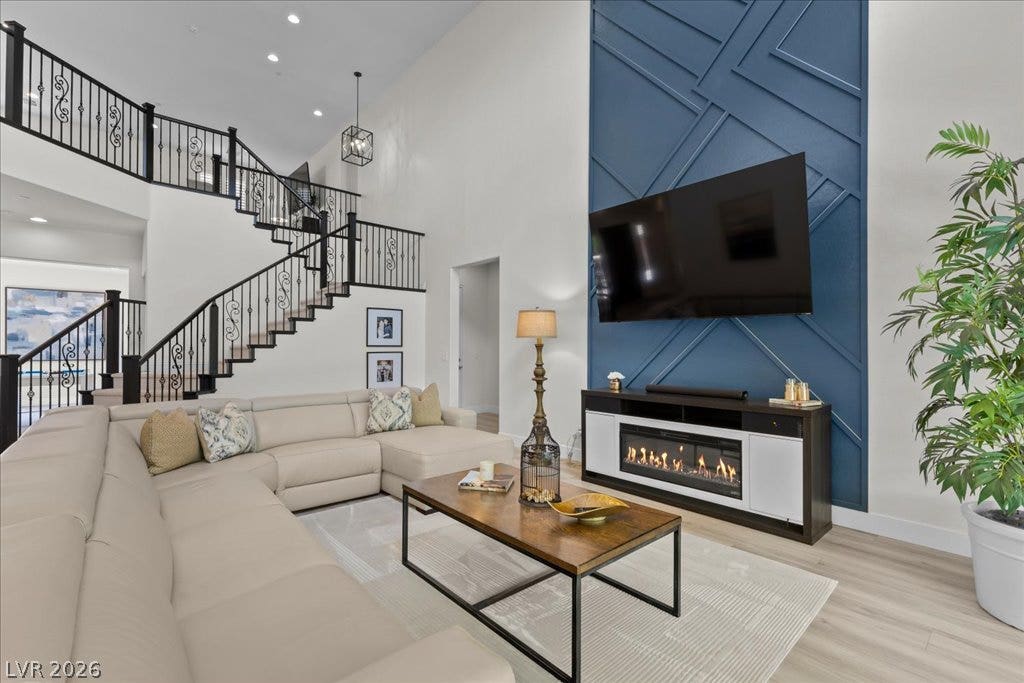 2828 Josephine Drive, Henderson, NV 89044 Grand two-story living room with a striking geometric accent wall and elegant wrought iron staircase.