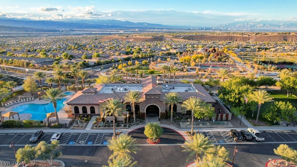 2828 Josephine Drive, Henderson, NV 89044 An inviting community clubhouse with a sparkling pool sits among verdant landscaping, surrounded by a thriving neighborhood and distant mountains.