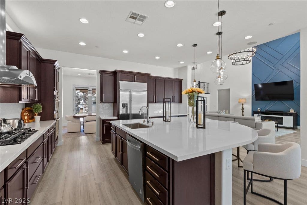 2828 Josephine Drive, Henderson, NV 89044 An open-concept kitchen boasts rich cabinetry, sleek countertops, and modern appliances, seamlessly flowing into a sun-filled living area with architectural wall detailing.