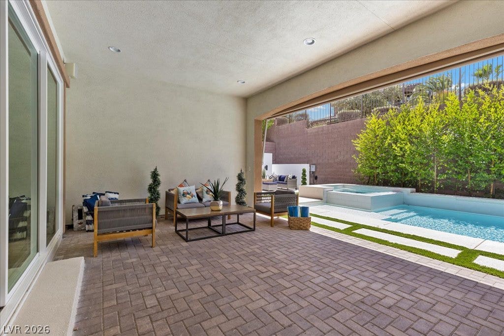 2828 Josephine Drive, Henderson, NV 89044 An inviting covered patio featuring herringbone pavers leads to a sparkling pool and spa, ideal for outdoor leisure.