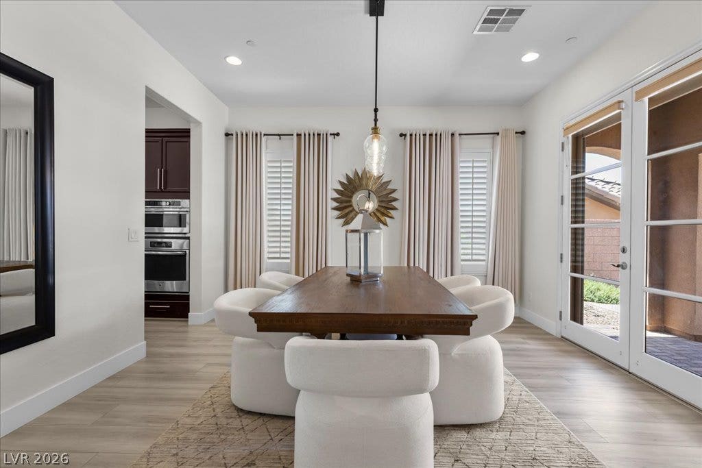 2828 Josephine Drive, Henderson, NV 89044 A refined dining space features a robust wooden table, plush seating, and access to the outdoors through elegant glass doors, protected with rolling metal shutters