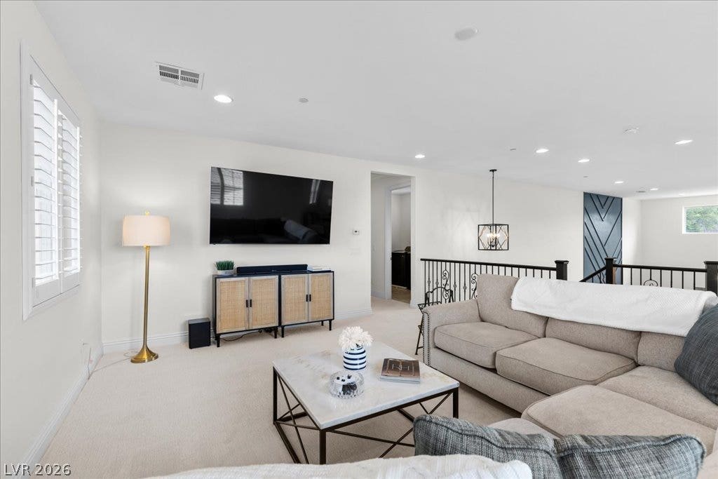 2828 Josephine Drive, Henderson, NV 89044 A comfortable upstairs living area offers a plush carpet, recessed lighting, and a modern chandelier, perfect for relaxation.