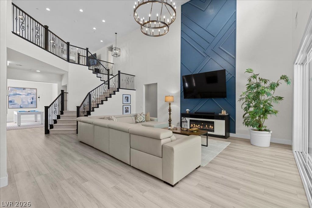 2828 Josephine Drive, Henderson, NV 89044 A grand, naturally illuminated living area showcases a dramatic two-story fireplace, wood flooring, and an elegant staircase.