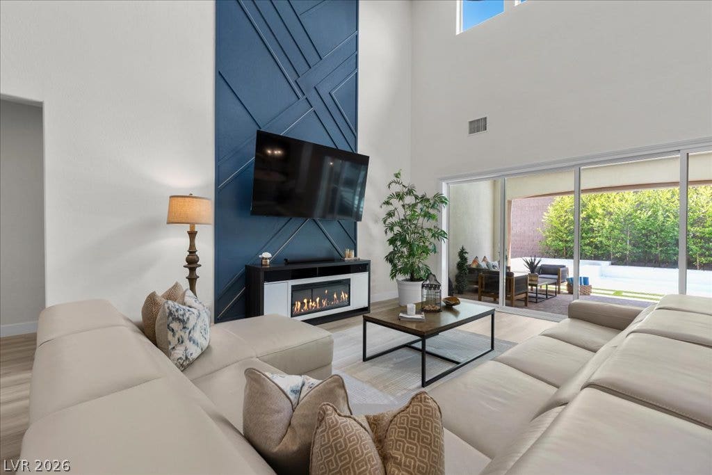 2828 Josephine Drive, Henderson, NV 89044 Sun-filled great room with soaring ceilings and a modern fireplace, offering seamless access to an inviting outdoor living space.