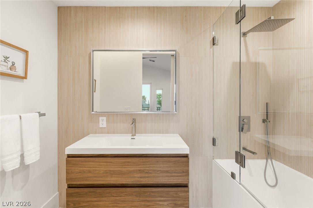 Modern bath features a rain shower and a sleek vanity with ample storage.
