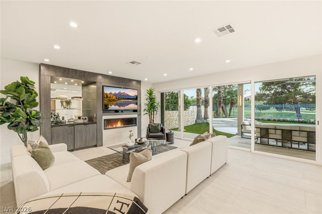A spacious, naturally illuminated living area flows seamlessly to the outdoor living space through expansive sliding glass doors.