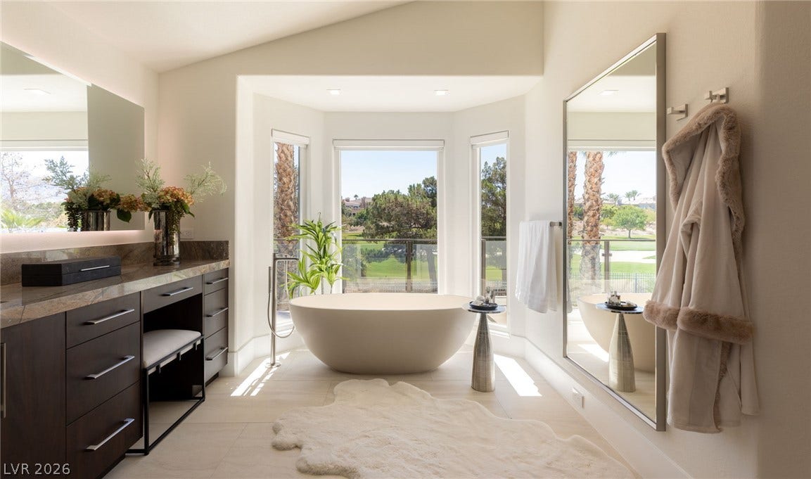 A spacious bathroom features a freestanding tub positioned to enjoy expansive outdoor views.