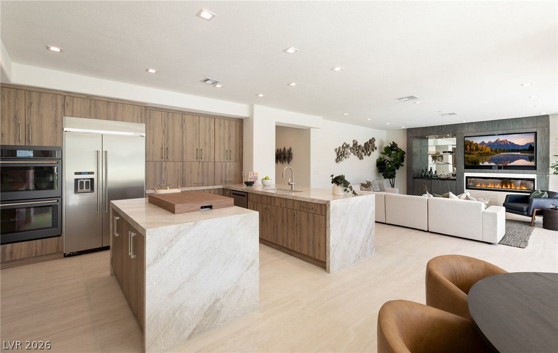 An open concept design seamlessly connects the culinary space to a comfortable living area with a contemporary fireplace.