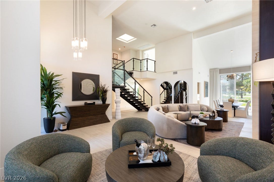 Sun-filled open-concept living space boasts soaring ceilings, sleek staircase, and expansive views.