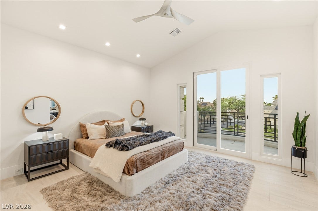 A tranquil bedroom retreat features a private balcony and a soft, plush area rug.
