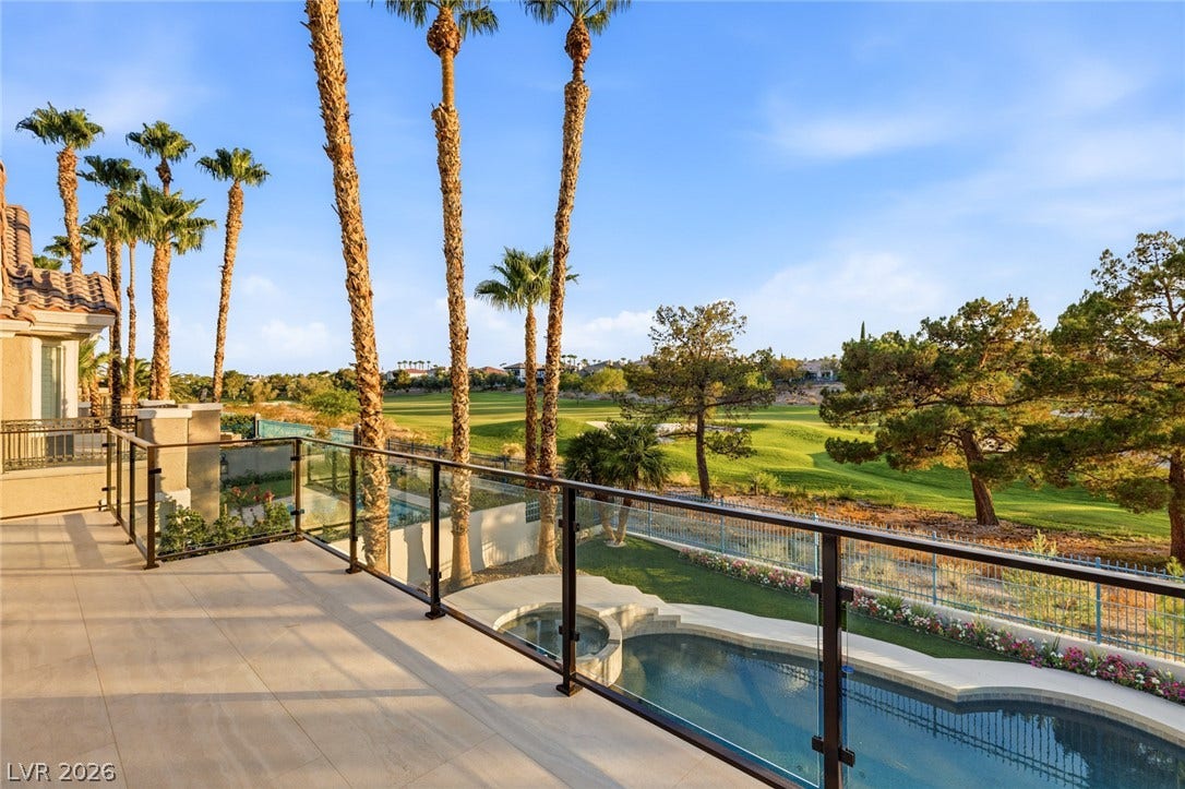 An inviting patio space boasts a refreshing pool and spa, overlooking a lush golf course with distant palms.
