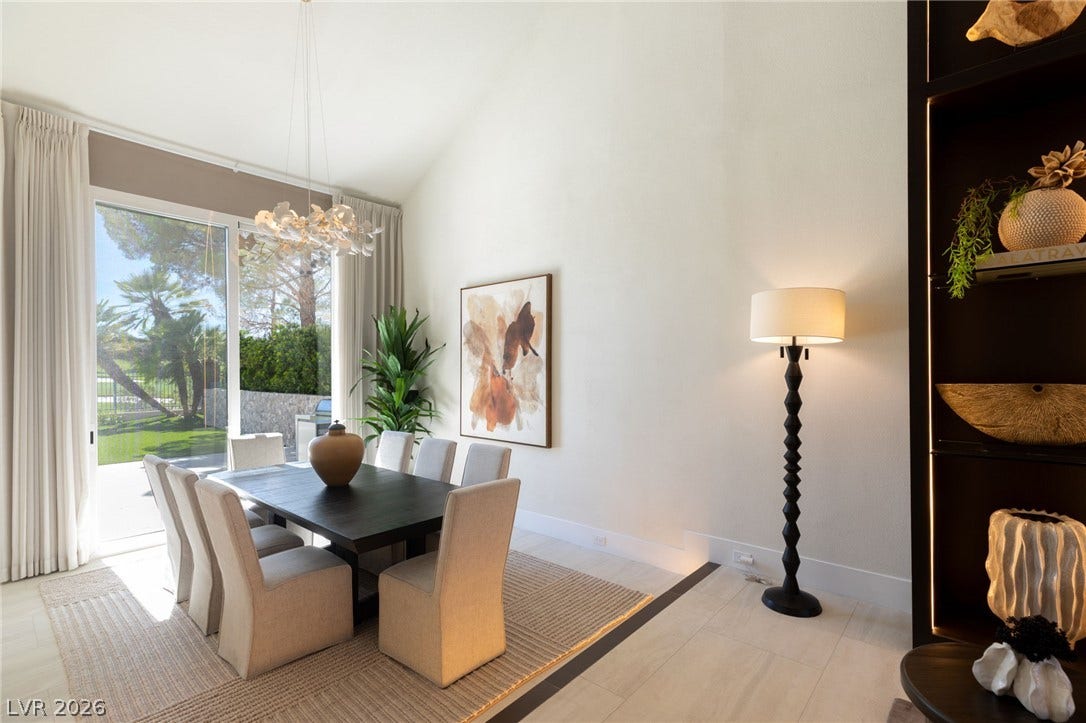 Natural light streams into this elegant dining area, boasting vaulted ceilings and seamless outdoor access.