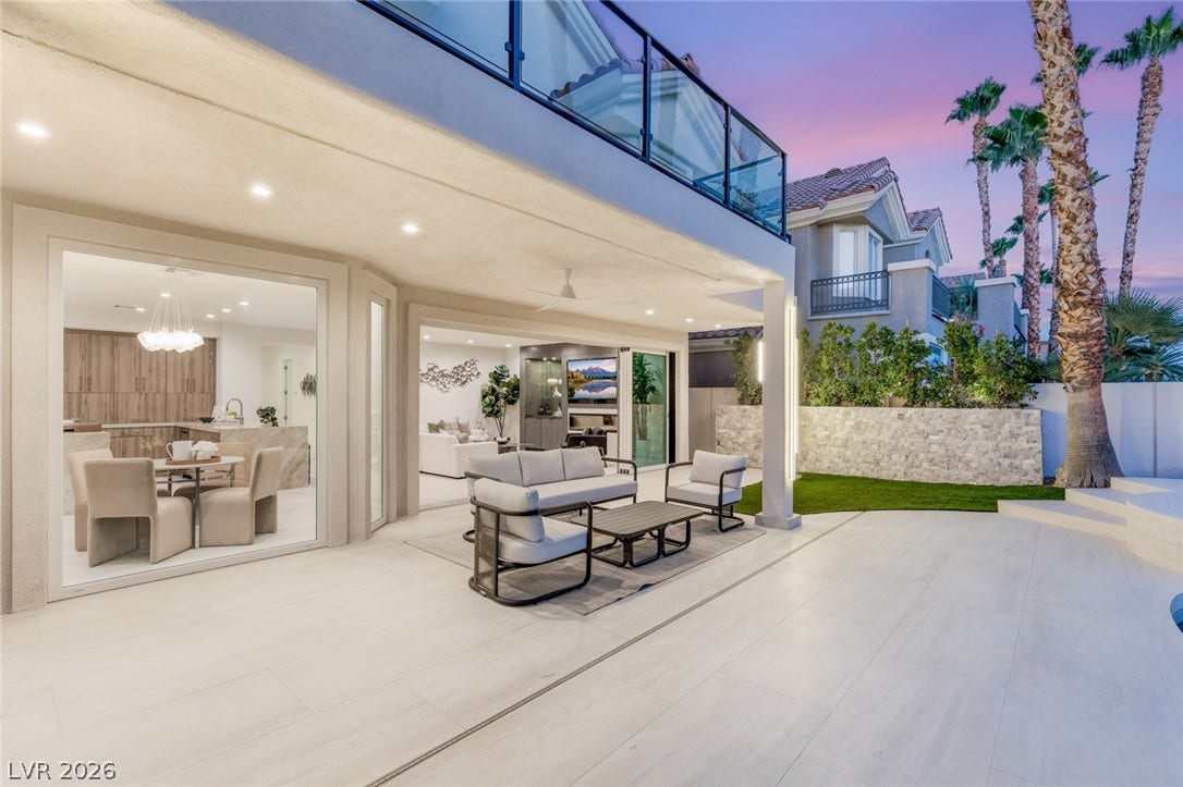 An inviting outdoor living space features an elegant seating area, patio, and lush landscaping.