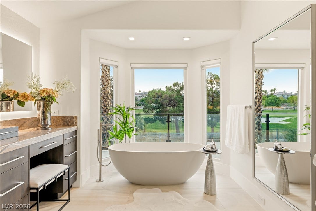 Indulge in a tranquil bathing experience with a freestanding tub overlooking verdant golf course vistas.