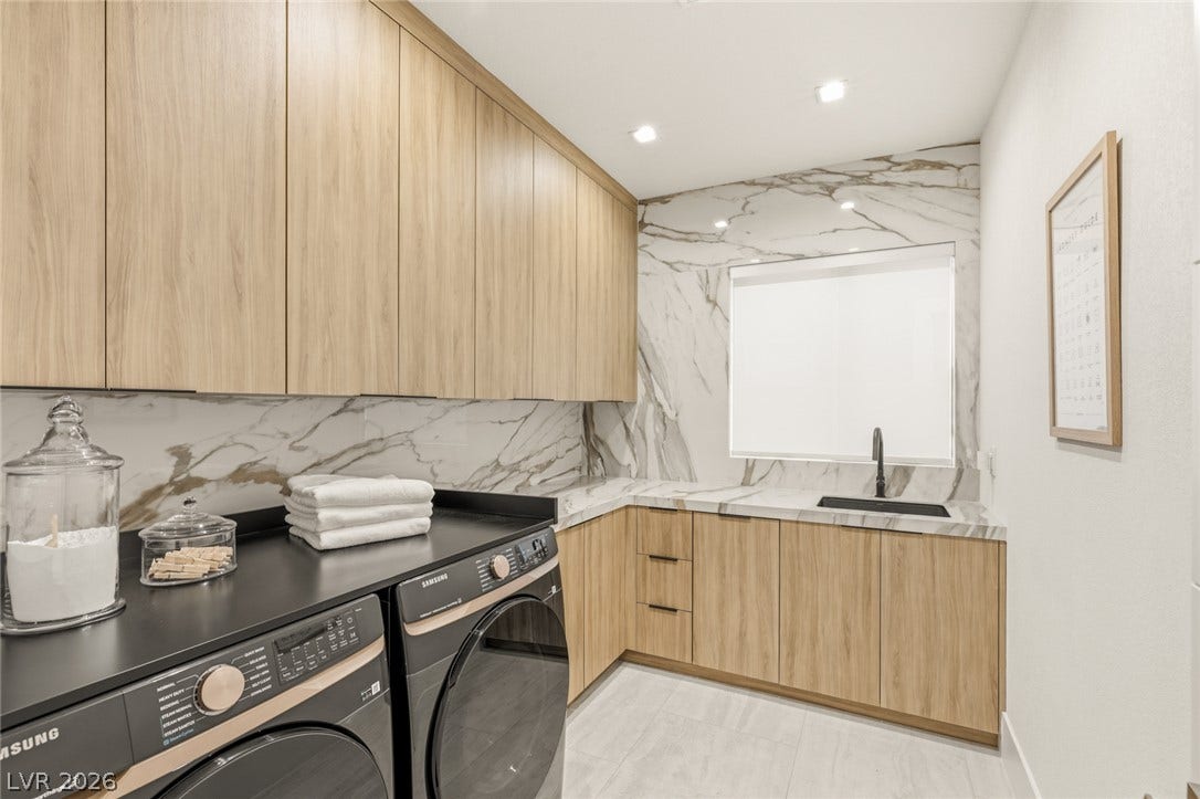 A well-appointed laundry room features ample cabinetry, a dedicated sink, and elegant marble accents.
