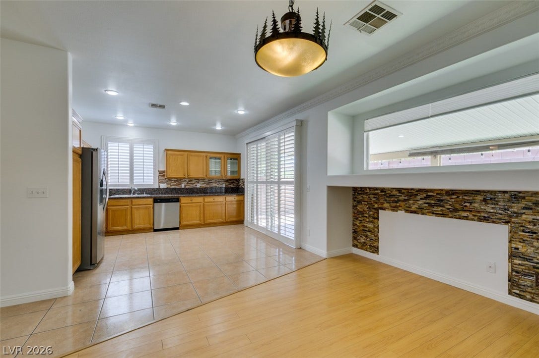 10513 Shanna Trellis Avenue, Las Vegas, NV 89144 Kitchen with dark countertops, tasteful backsplash, stainless steel appliances, light tile patterned floors, and ornamental molding