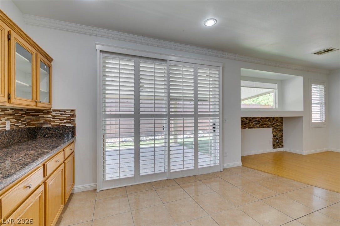 10513 Shanna Trellis Avenue, Las Vegas, NV 89144 Kitchen with ornamental molding, light tile patterned floors, decorative backsplash, glass insert cabinets, and dark stone counters