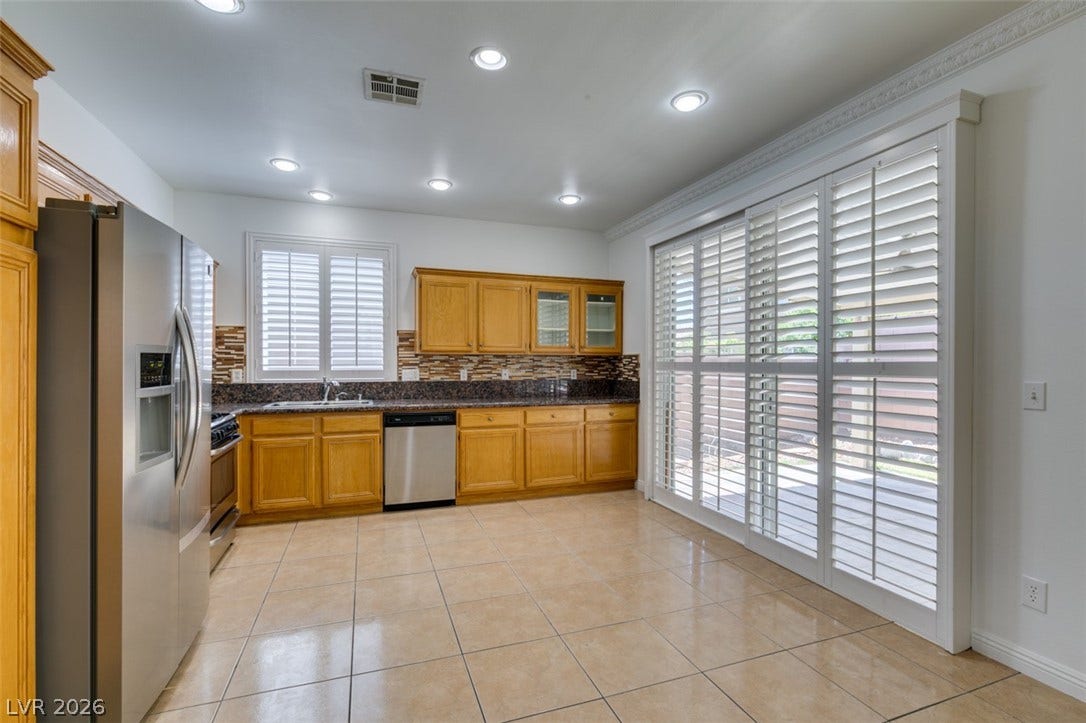 10513 Shanna Trellis Avenue, Las Vegas, NV 89144 Kitchen with appliances with stainless steel finishes, light tile patterned floors, decorative backsplash, glass insert cabinets, and brown cabinets