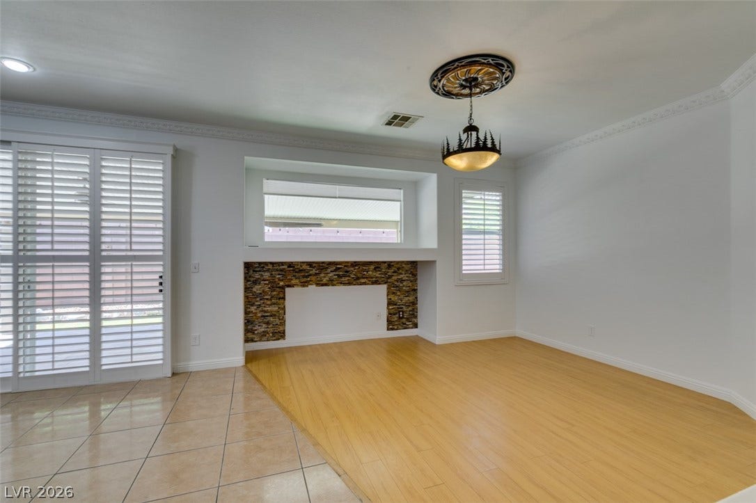 10513 Shanna Trellis Avenue, Las Vegas, NV 89144 Unfurnished living room featuring light wood-style flooring, crown molding, and a fireplace