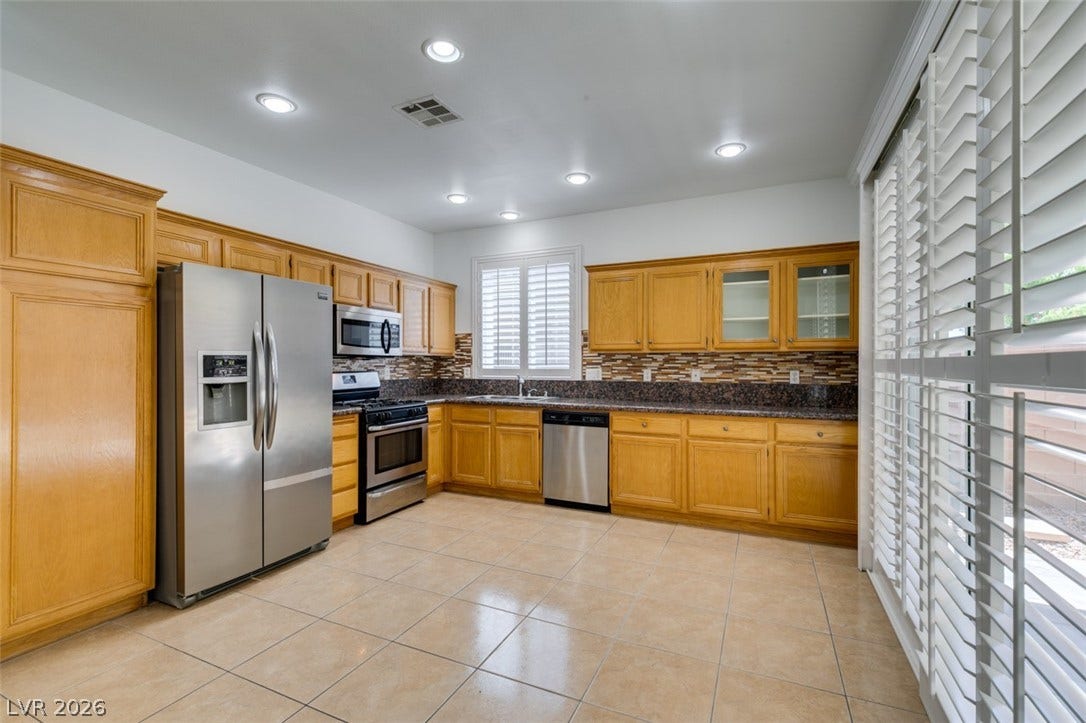 10513 Shanna Trellis Avenue, Las Vegas, NV 89144 Kitchen with stainless steel appliances, decorative backsplash, light tile patterned flooring, recessed lighting, and glass insert cabinets