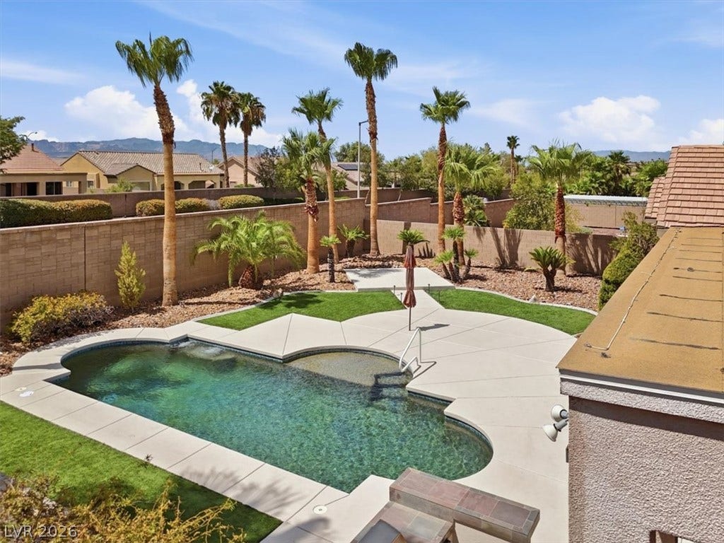 Palm trees surround an inviting swimming pool inside a private, walled backyard oasis.