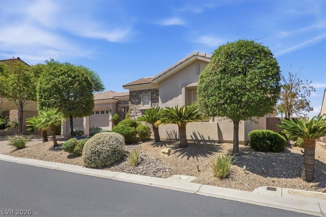 Manicured desert landscaping and stone accents frame this inviting single-story residence.