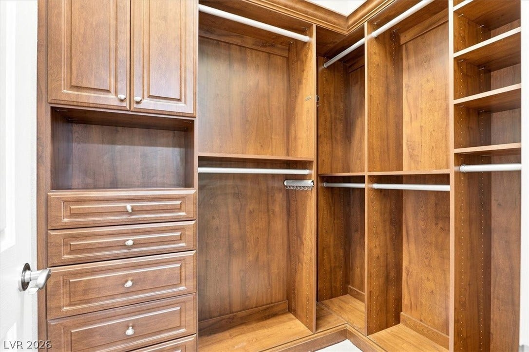 Rich wood cabinetry and built-in shelving maximize storage space in this organized closet.
