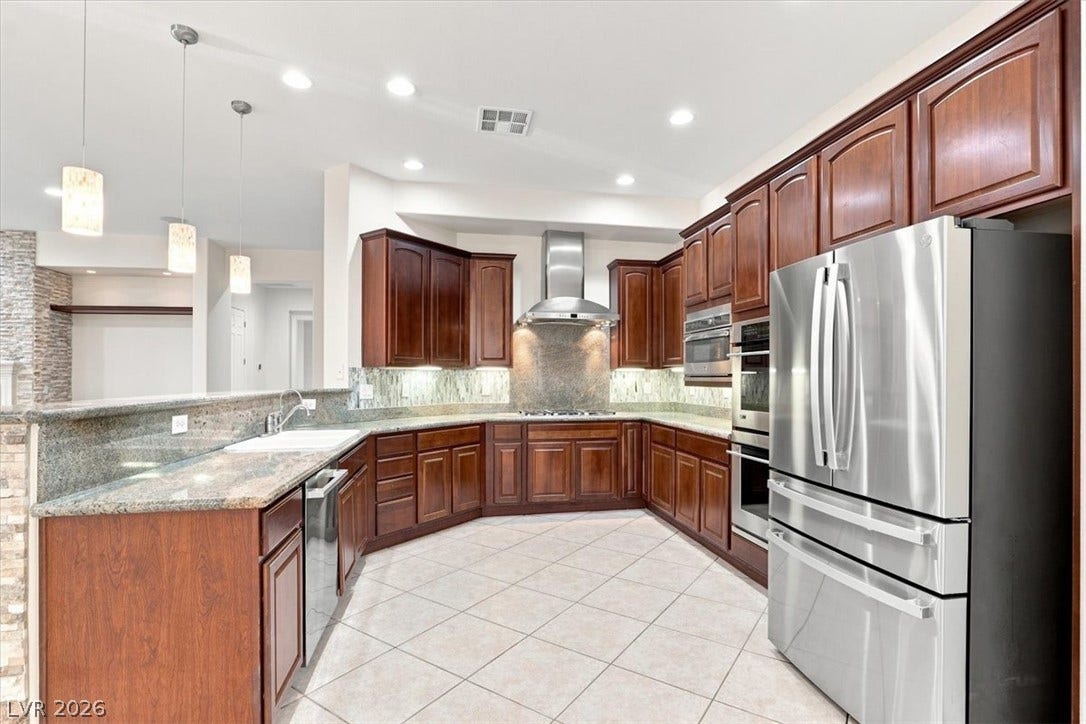 Rich wood cabinetry paired with granite countertops defines this well-appointed kitchen workspace.