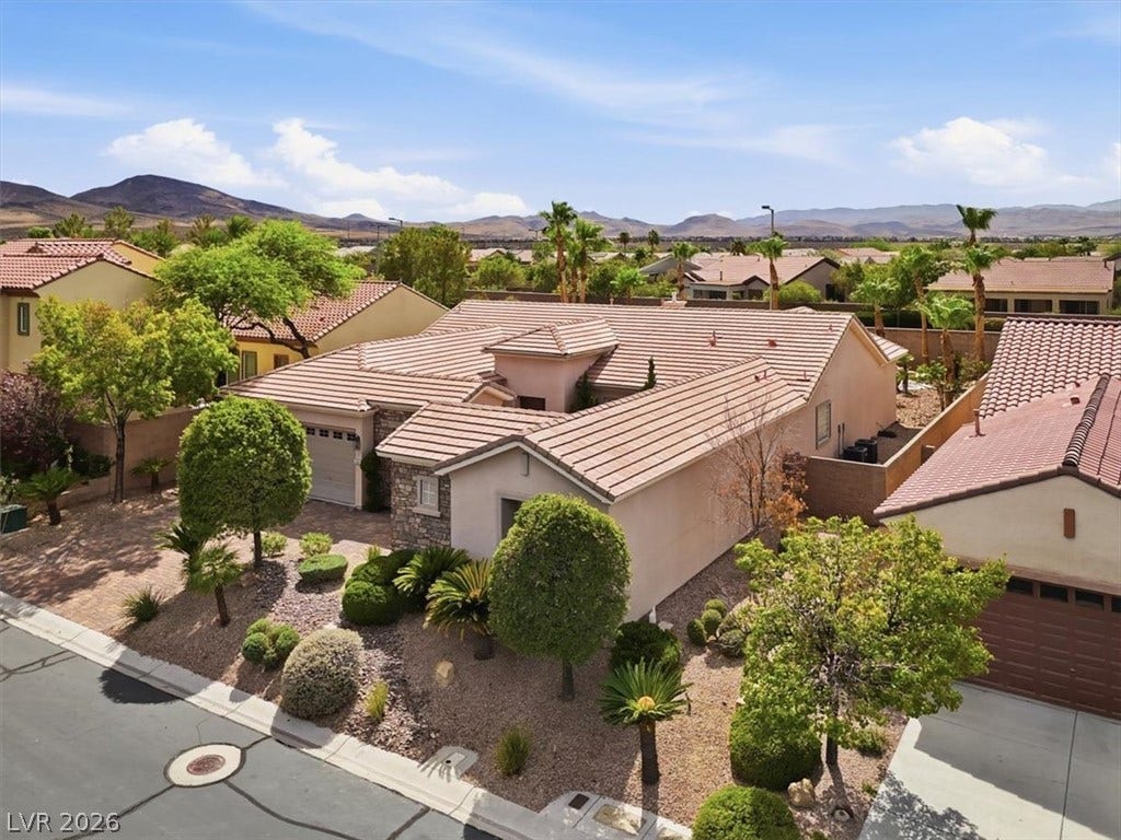 Manicured desert landscaping frames a classic tile roof structure set against scenic mountain backdrops.