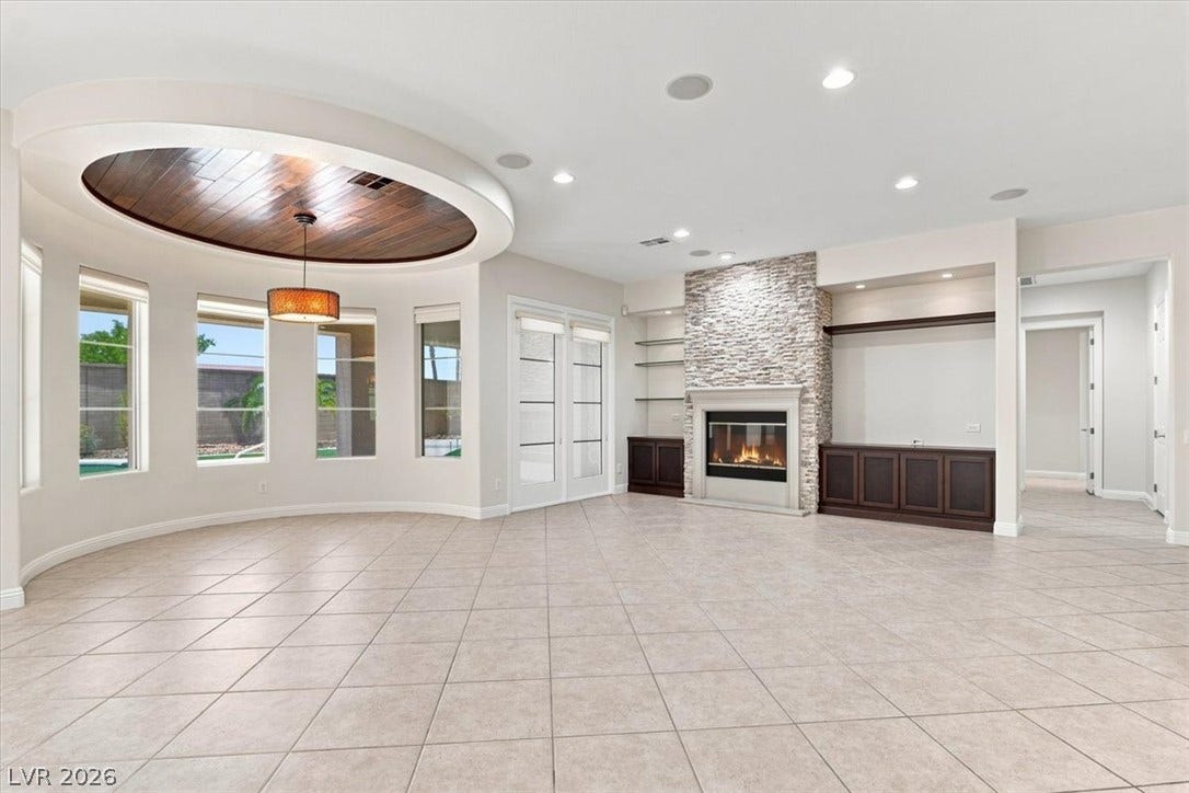Tiled floors and a stone fireplace define this open living space with inset wood ceiling detail.