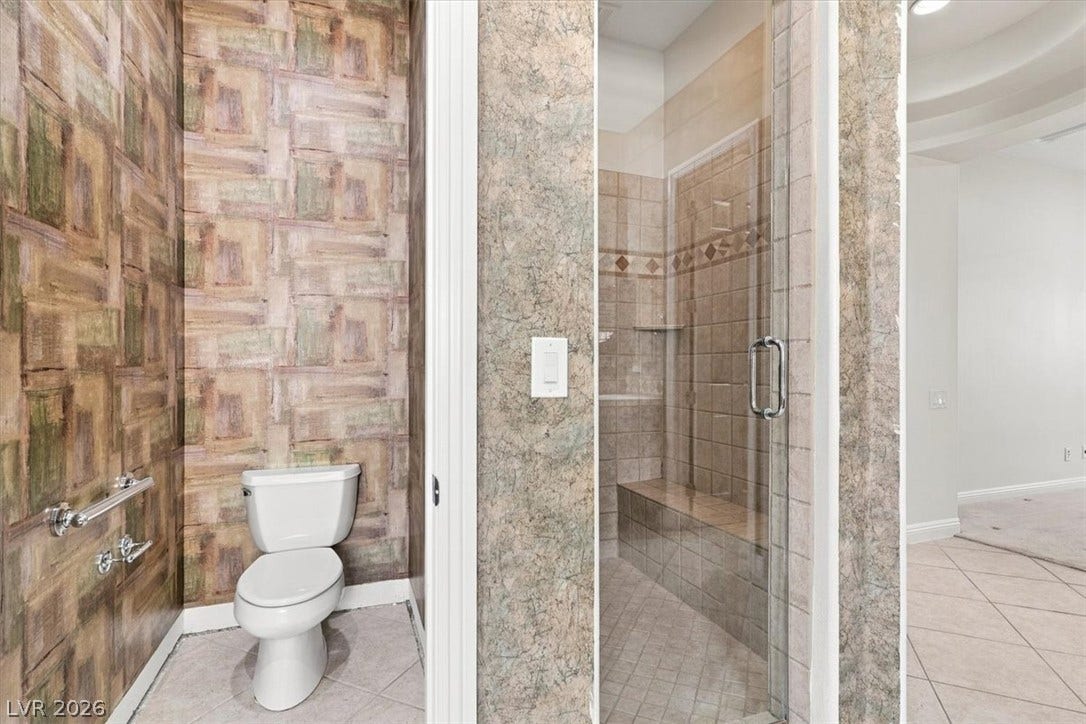 Textured wall coverings frame a tiled walk-in shower with a built-in bench seat.