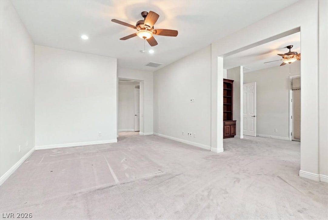 Plush carpeting anchors this versatile living space featuring a wide arched opening to adjacent rooms.