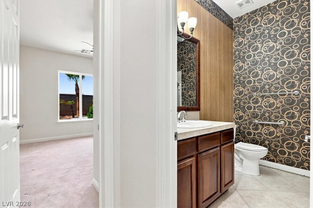 An adjacent carpeted room sits just off the bathroom featuring a dark wood vanity.