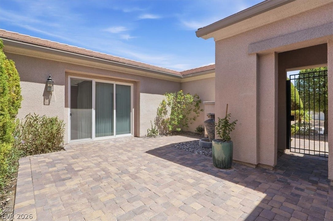A private paved courtyard entry leads to the residence under clear blue skies.