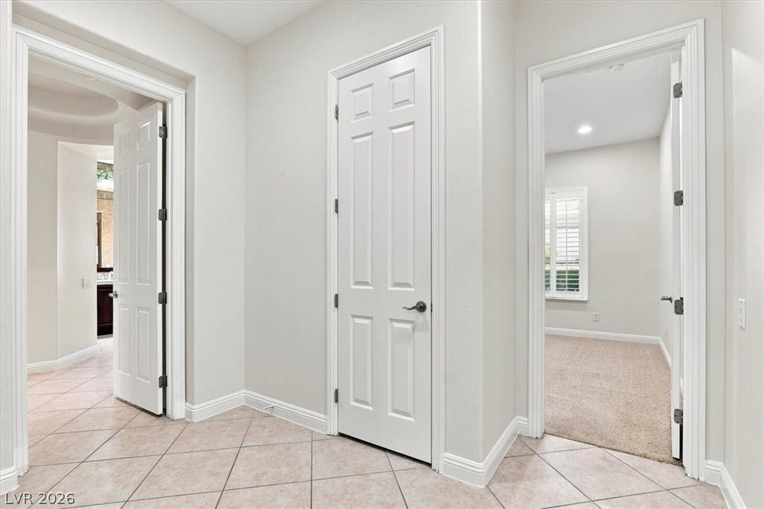 Tiled flooring and crisp white trim connect multiple rooms in this versatile hallway layout.