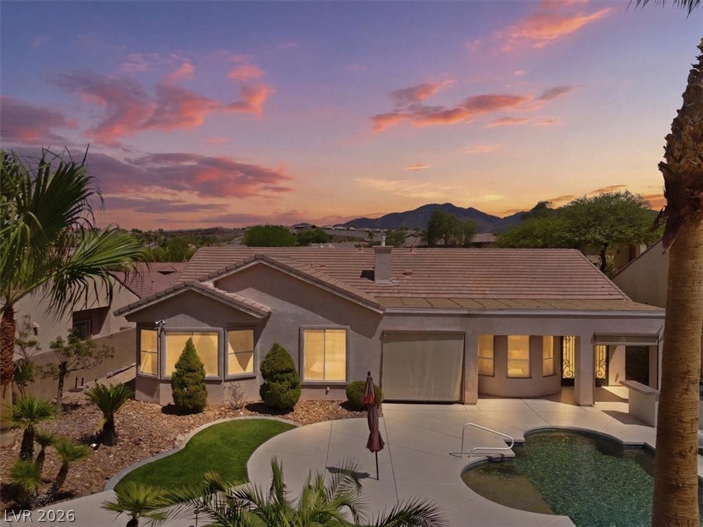 Dusk skies frame a tiled roofline, paved patio, and sparkling pool set against mountain vistas.