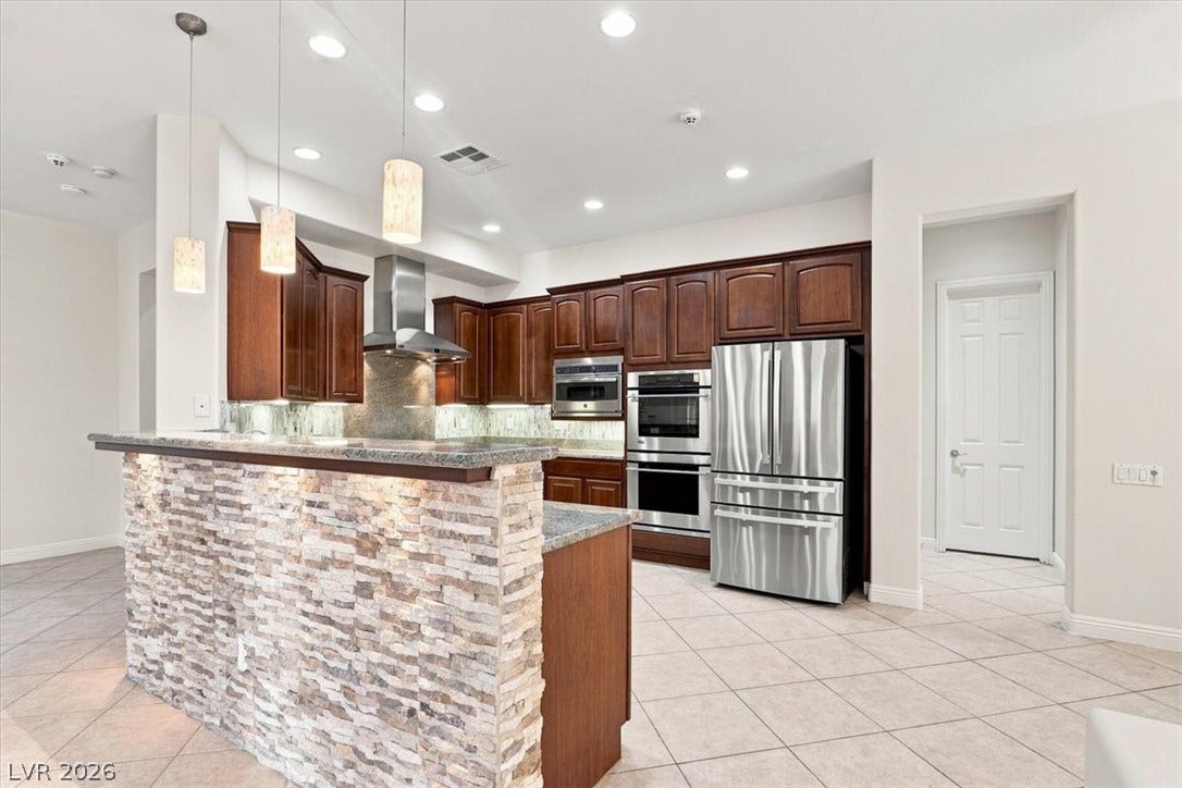 Rich wood cabinetry contrasts beautifully with a stone-clad breakfast bar and tile flooring.