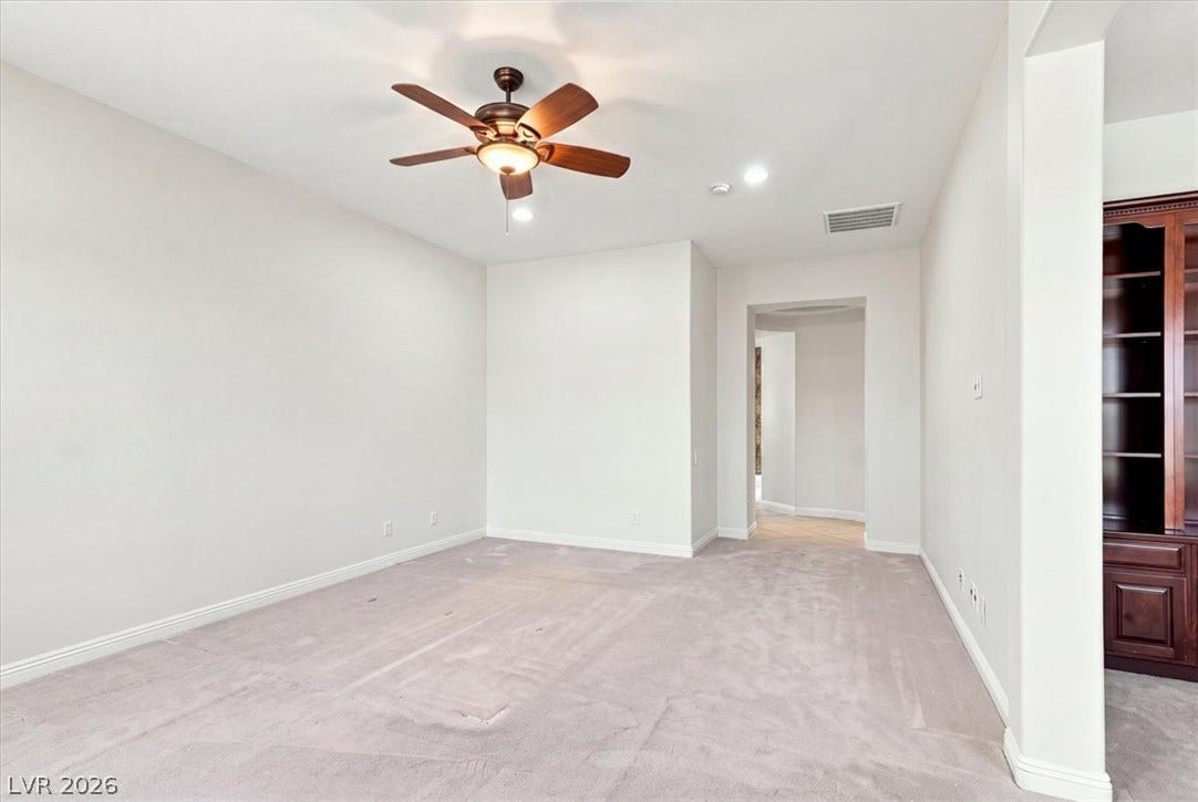 An open doorway connects plush carpeted rooms under smooth plaster ceilings.