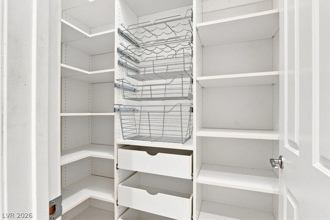 Custom storage shelving and pull-out baskets maximize organization inside this walk-in closet space.