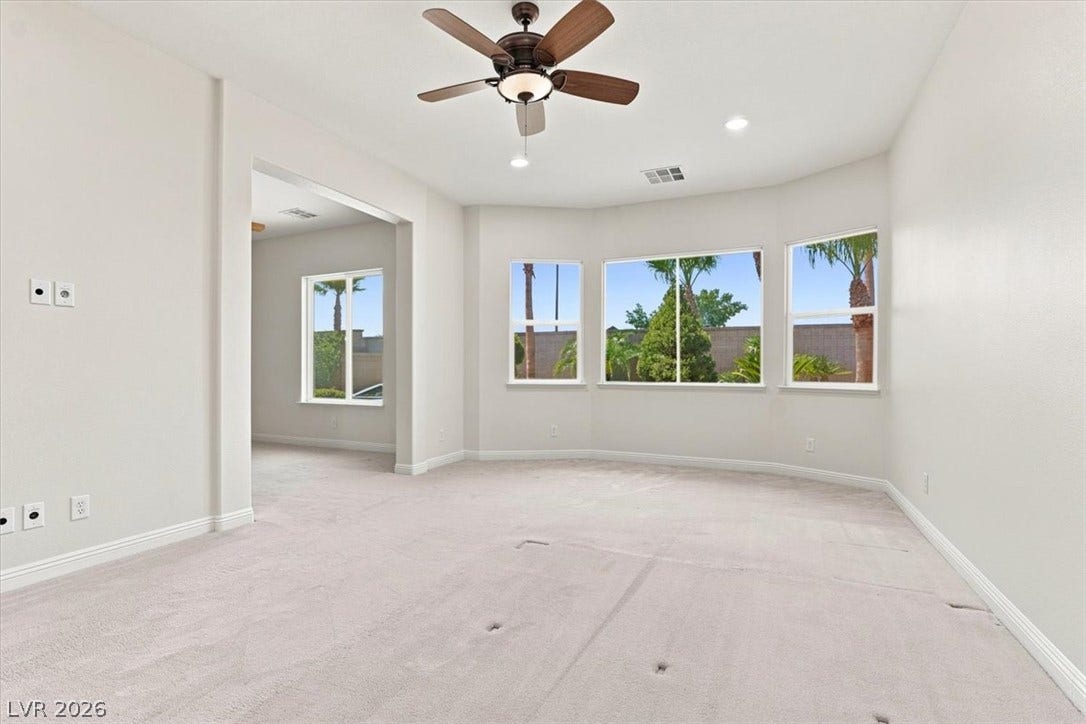 Bay windows overlook the backyard from this light-filled room with neutral carpet.