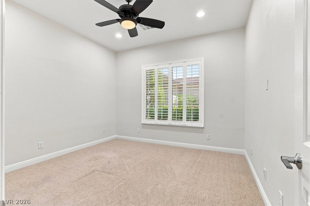 High ceilings and clean walls create a serene atmosphere in this carpeted secondary bedroom.