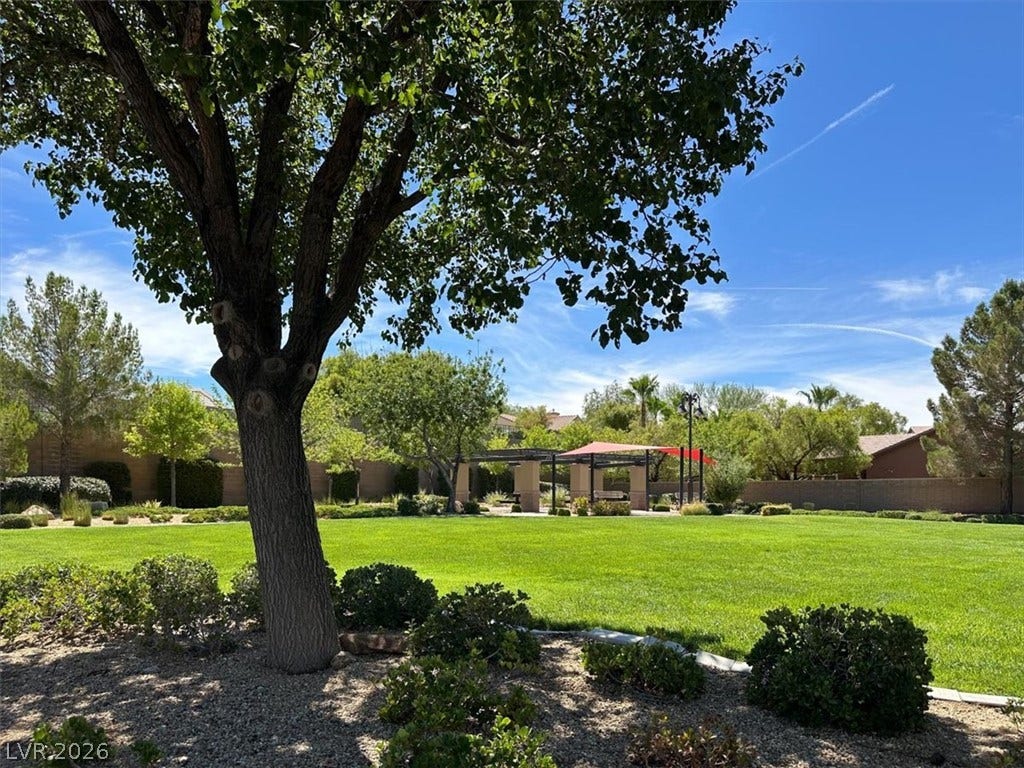 Mature trees shade a manicured lawn leading toward community pavilions.