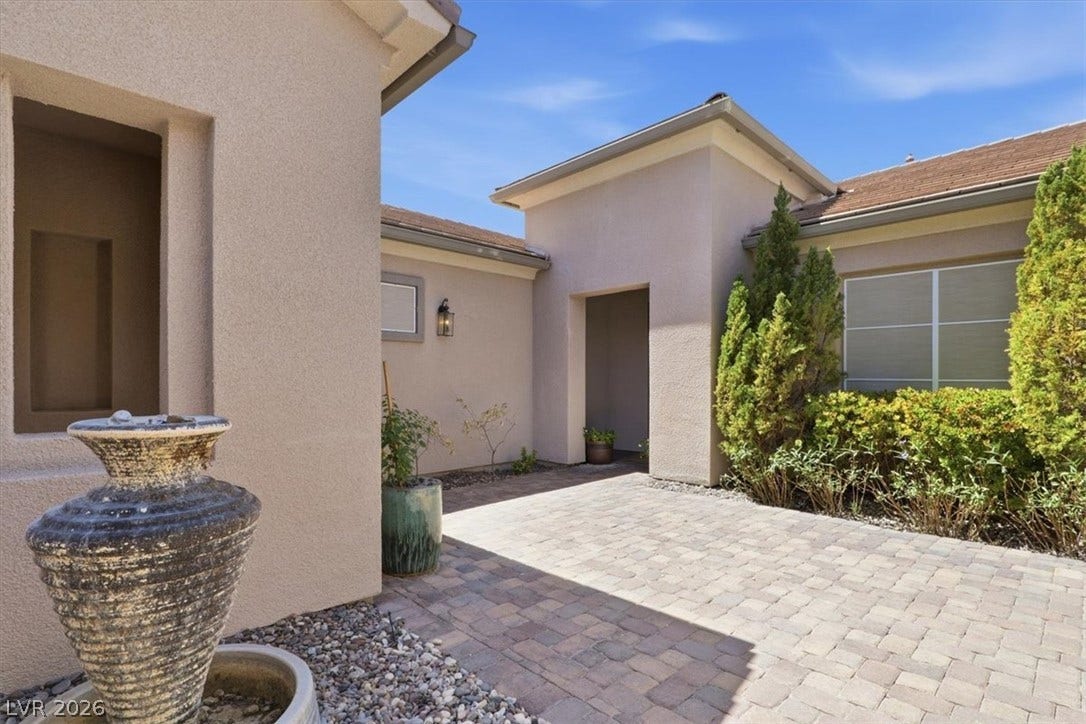 An inviting stone-paved courtyard welcomes guests to the elegant stucco exterior.