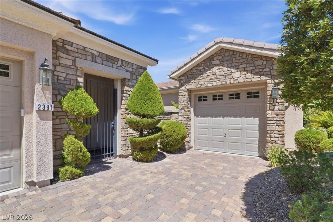 Textured stone accents and a paved driveway create an inviting arrival experience.