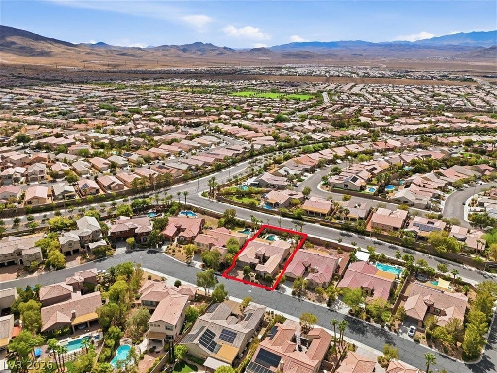 Aerial view captures a master-planned neighborhood framed by distant desert mountains.