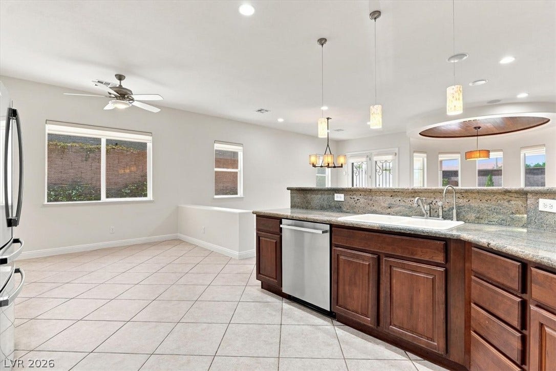 An open kitchen featuring classic wooden cabinetry, granite countertops, and seamless tile flooring.
